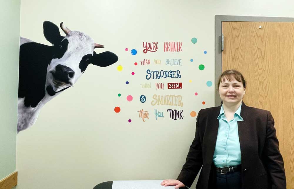 Dr. Marchenko poses near a quote in the Pediatrics room "You are braver than you beliee stronger than you seem, and smarter than you think.